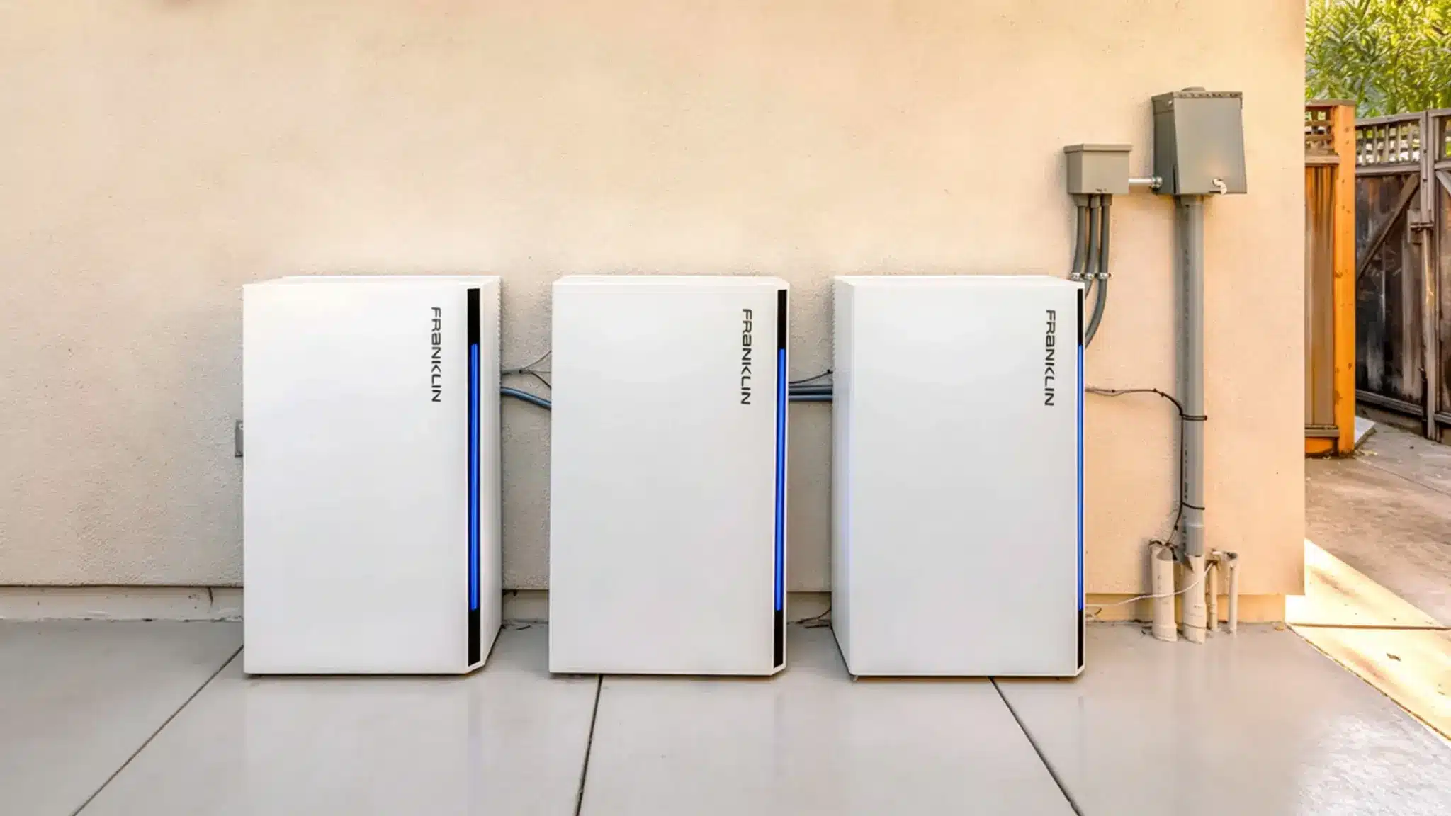 Three Franklin home battery storage units mounted outdoors against a wall with electrical conduit connections.