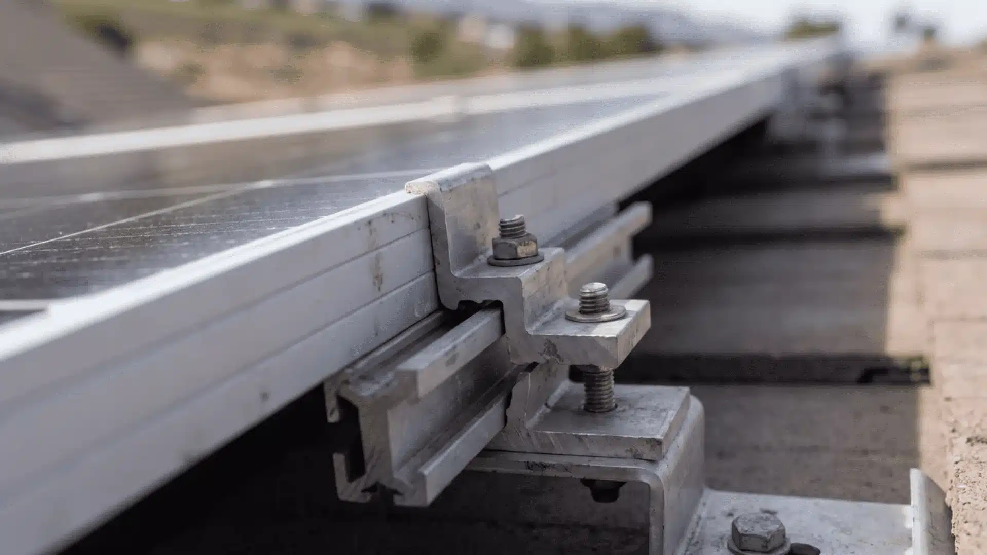 Close-up of a solar panel mounting rail and clamp attached to a roof.