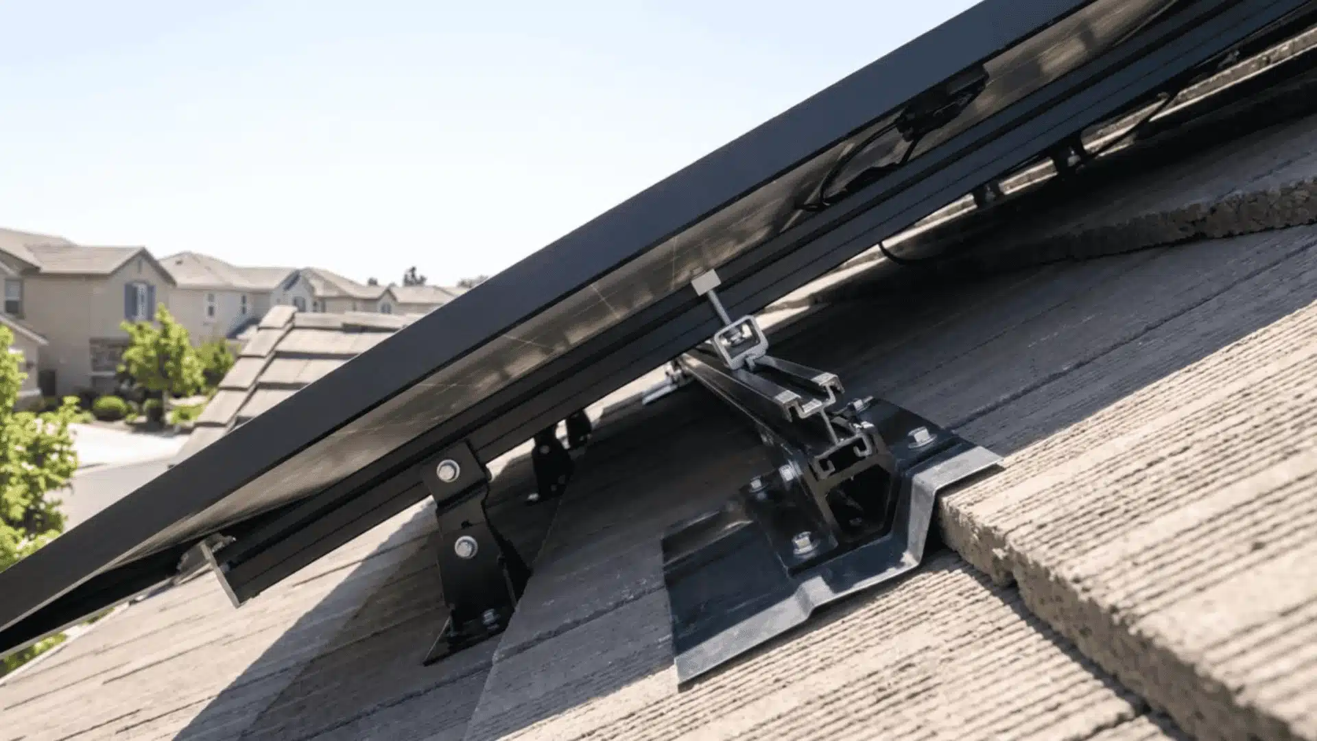 Close-up of rooftop solar panel mounting brackets showing the panel's tilt angle.