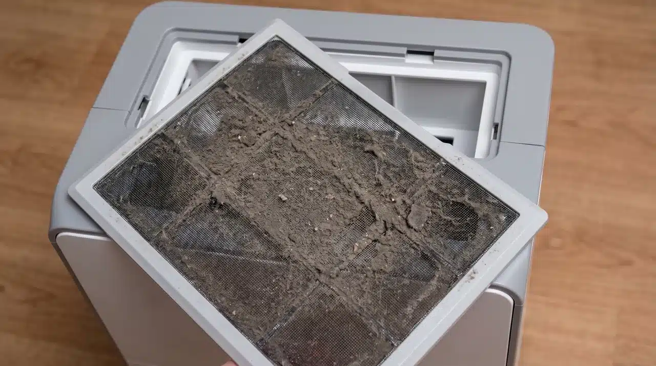 Dusty dehumidifier filter removed from unit during routine maintenance cleaning