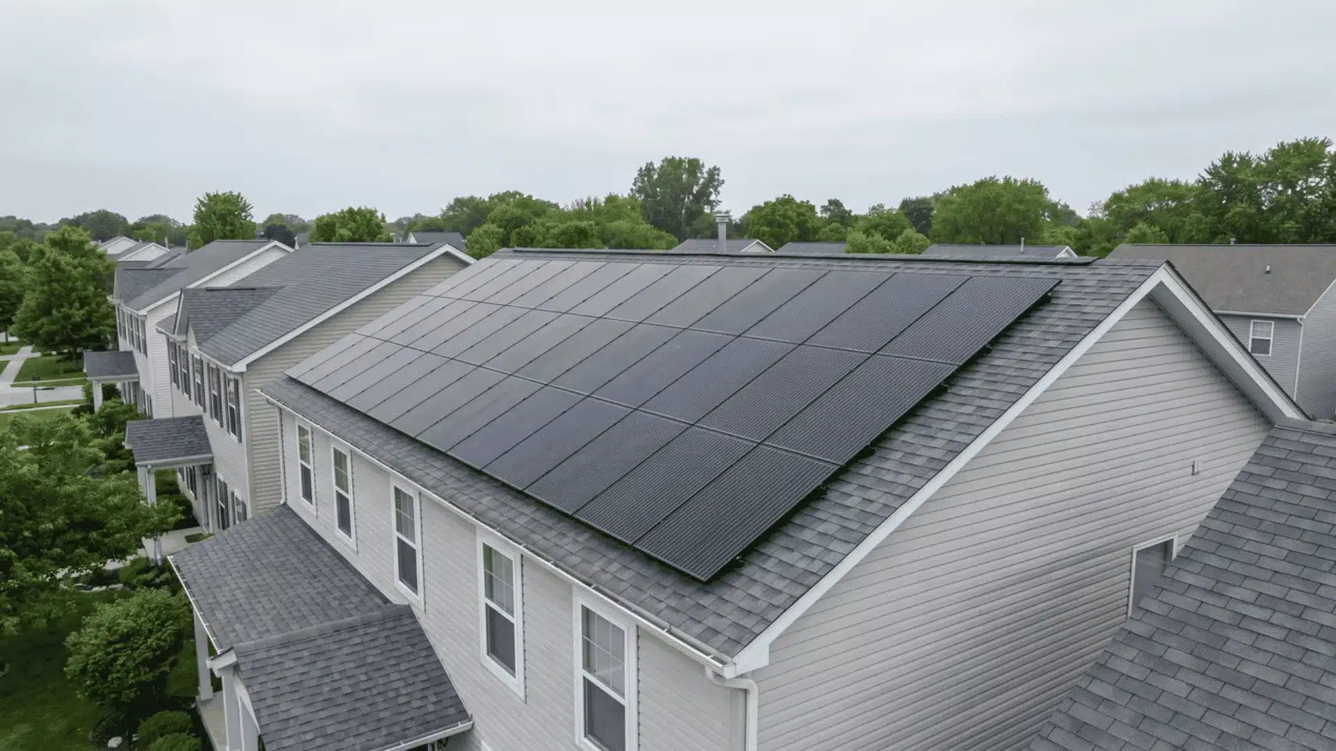 Solar panels covering residential townhouse roofs in suburban neighborhood under cloudy sky