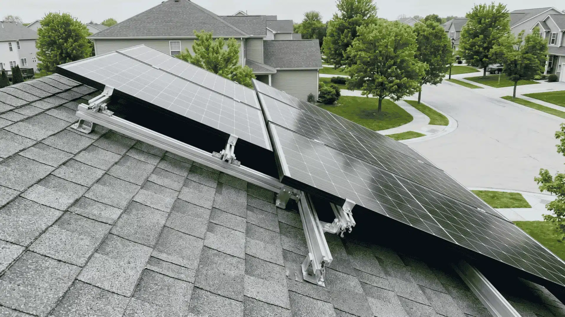 Angled close view of solar panels mounted on roof showing brackets with neighborhood street behind