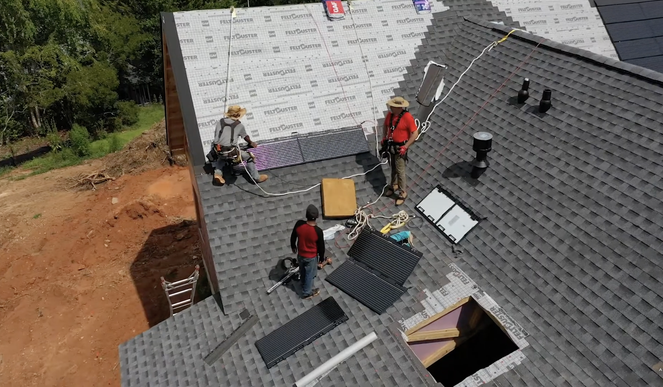 workers installing solar shingles on a residential roof with roofing materials, safety equipment, and panels during a home solar installation project