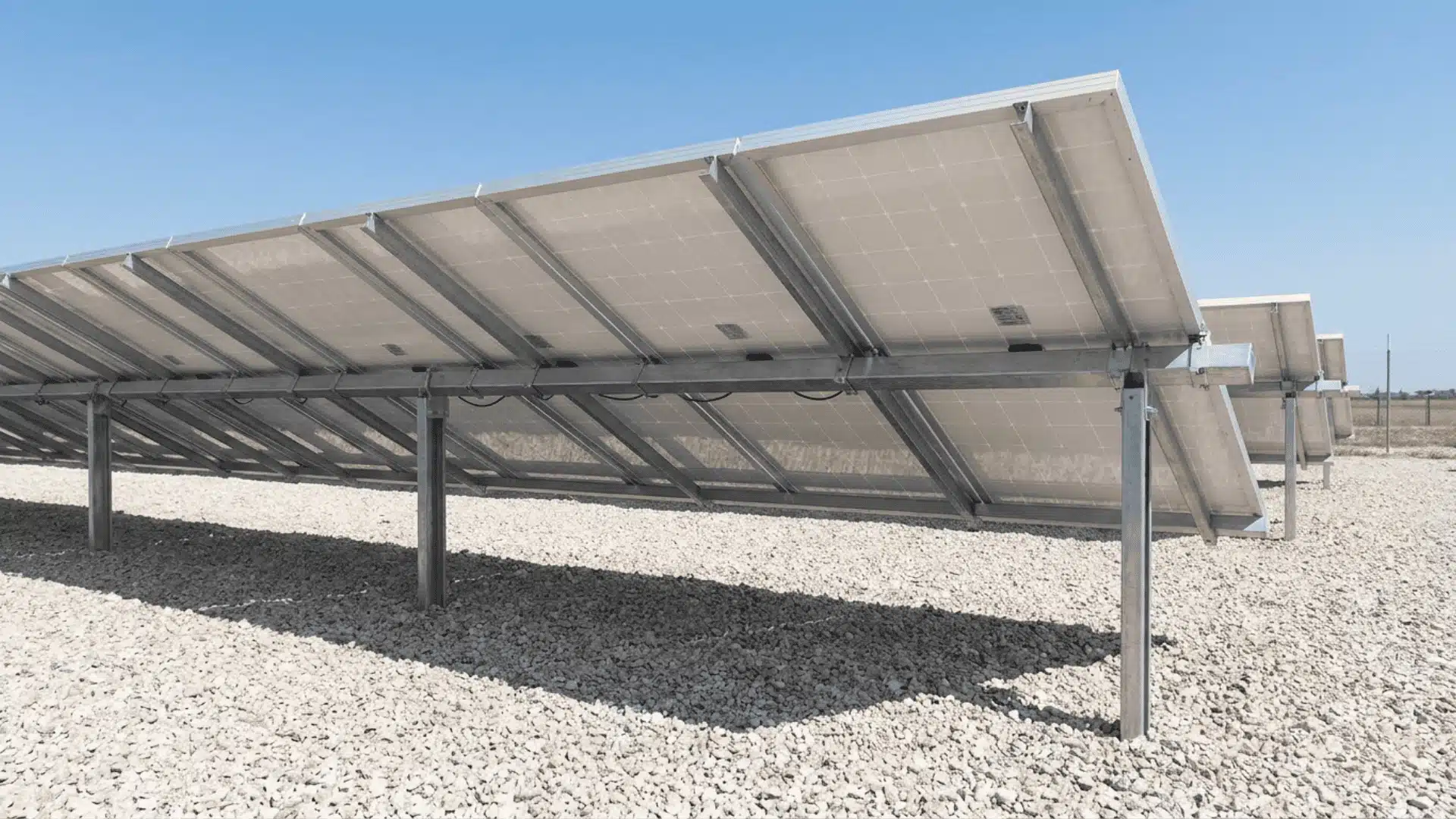 Raised bifacial solar panels above light-colored gravel