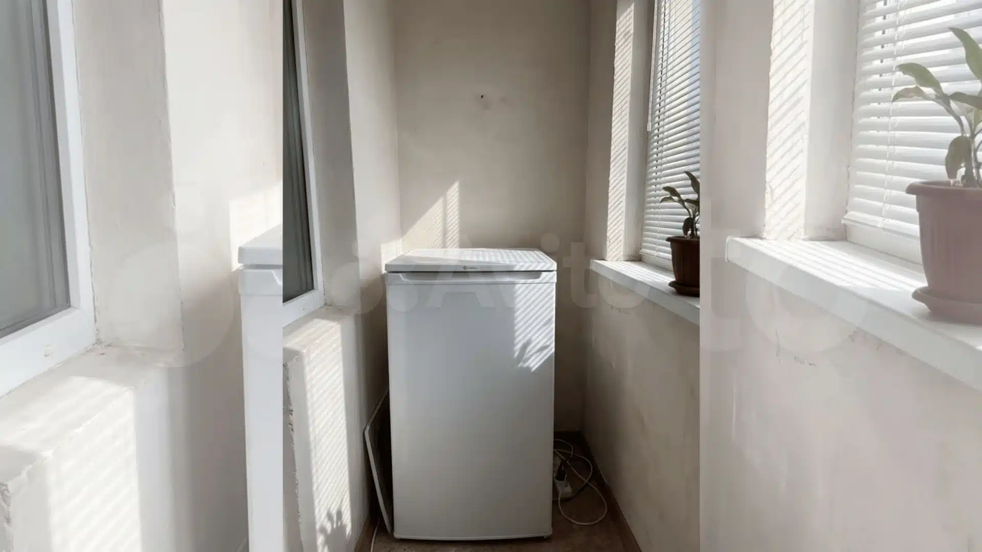 mini fridge pressed against a wall in a sunlit room corner