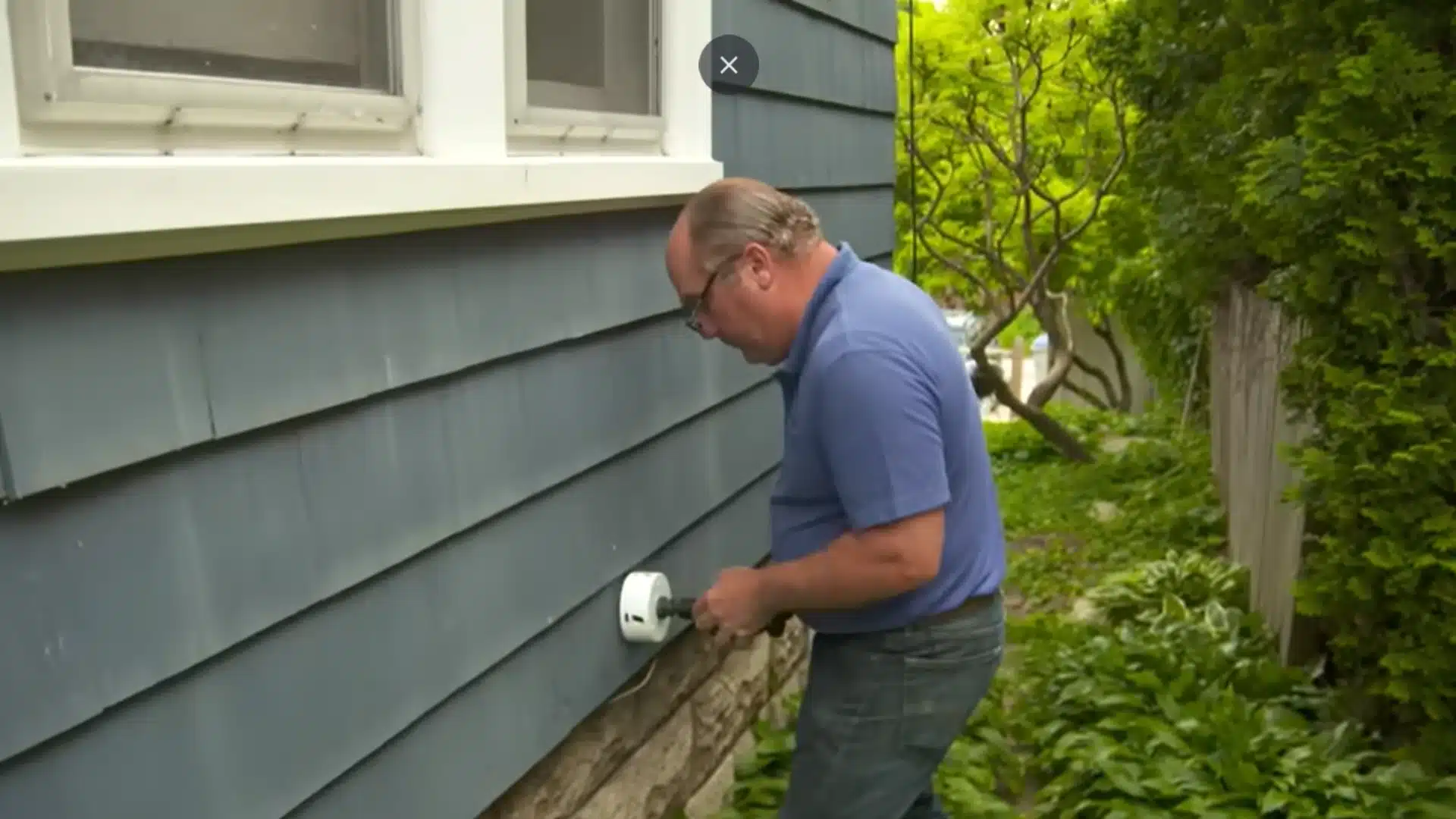 Technician checks an exterior intake and exhaust vent installed through home siding