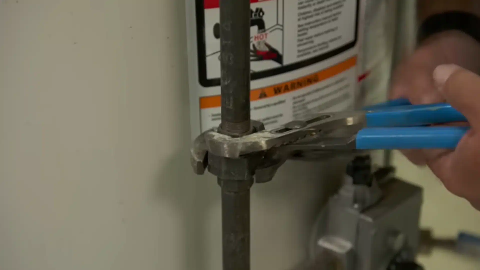 Technician loosens the gas pipe connection on an old basement water heater