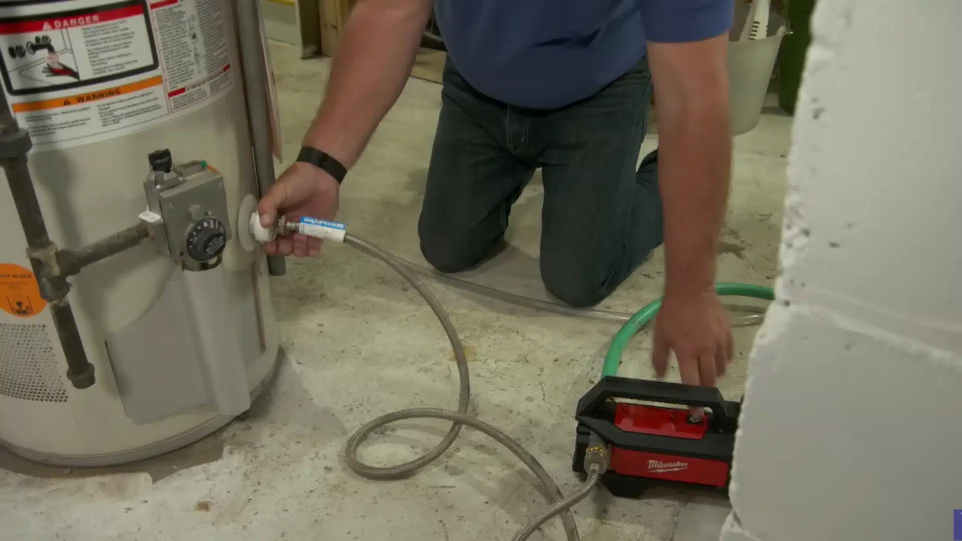 Technician drains an old water heater using a portable pump and connected hoses
