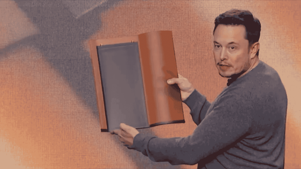 Elon Musk holding up a Tesla Solar Roof tile prototype on stage during a product presentation.