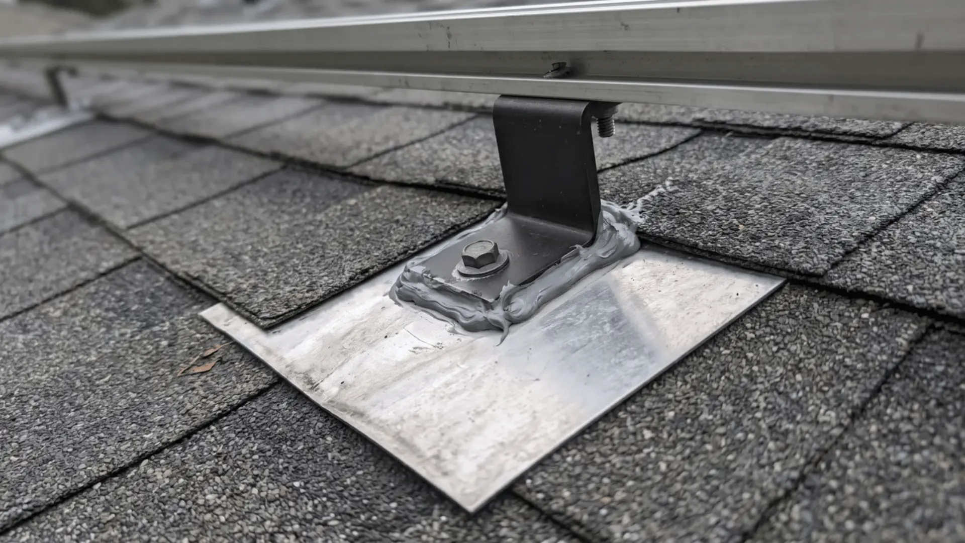 Solar roof mount secured over metal flashing and sealant on asphalt shingles